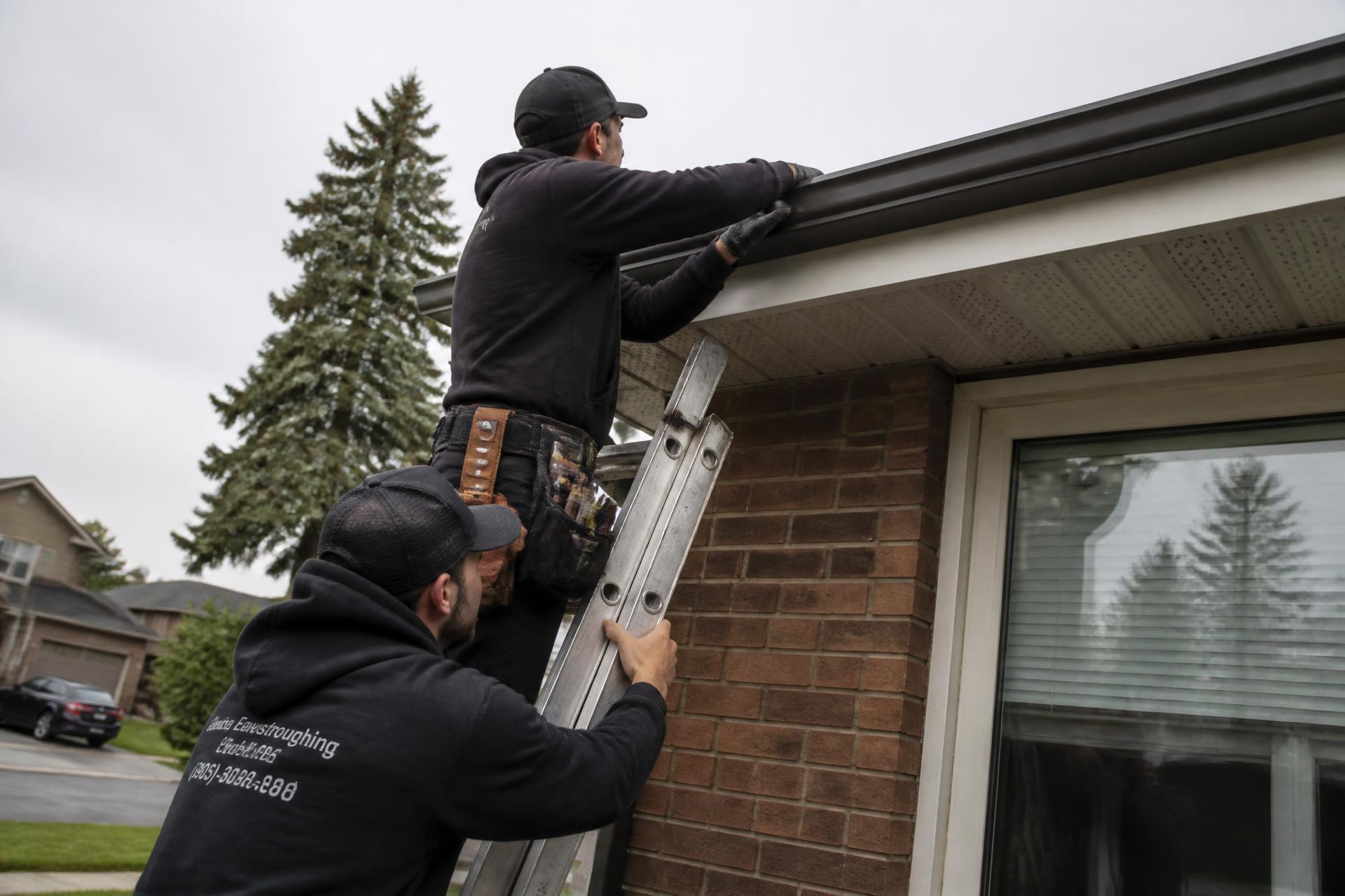 Crew installing seamless eavestrough on a brick home